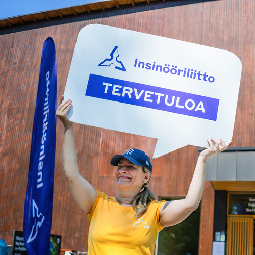 Henkilö näyttää Insinööriliiton Tervetuloa-kylttiä tapahtumaan osallistuville