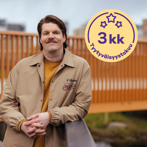 Oranssipaitainen henkilö nojaa kaiteeseen ja hymyilee kameralle.