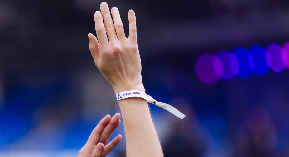 Lapsella on käsi ylhäällä. Ranteessa hänellä on tapahtumaranneke.