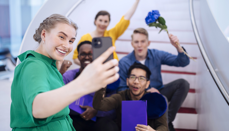 Vastavalmistuneet insinööriopiskelijat ottavat portaikossa selfietä. Opiskelijat nauravat ja tuulettavat.