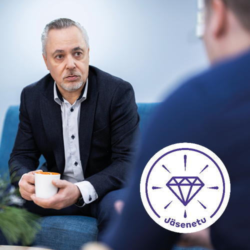 Henkilö keskustelee sohvalla kahvikuppi kädessään keskittyneesti.