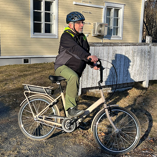 Mies poseeraa pyörän kanssa keväisessä maisemassa.