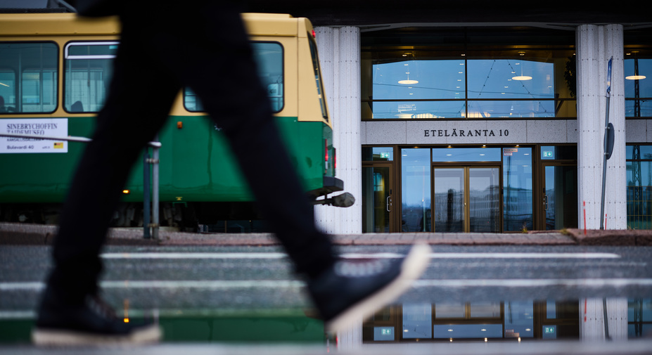 Raitiovaunu ja ihmisen jalat, tarkennus taustalla olevassa rakennuksessa.