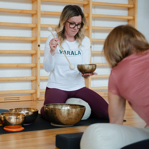 Henkilö salissa äänimaljojen kanssa. Varala.